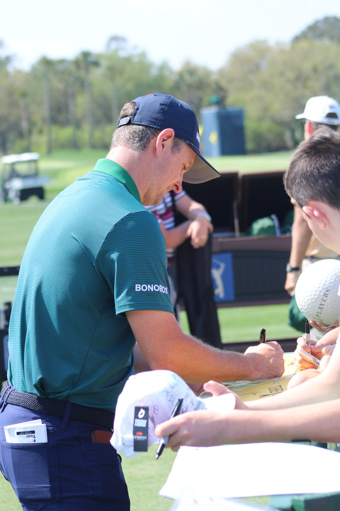 Justin Rose signs autographs for some young fans.